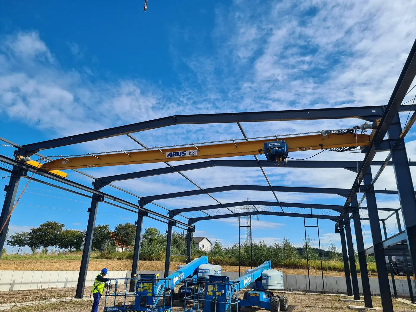 Steel frame of the hall with a yellow crane girder and aerial work platforms