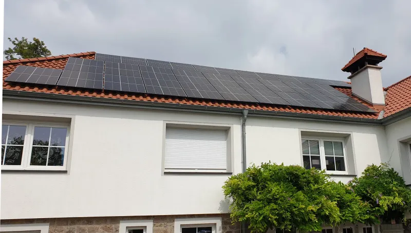 Weißes Haus mit PV auf dem roten Dach
