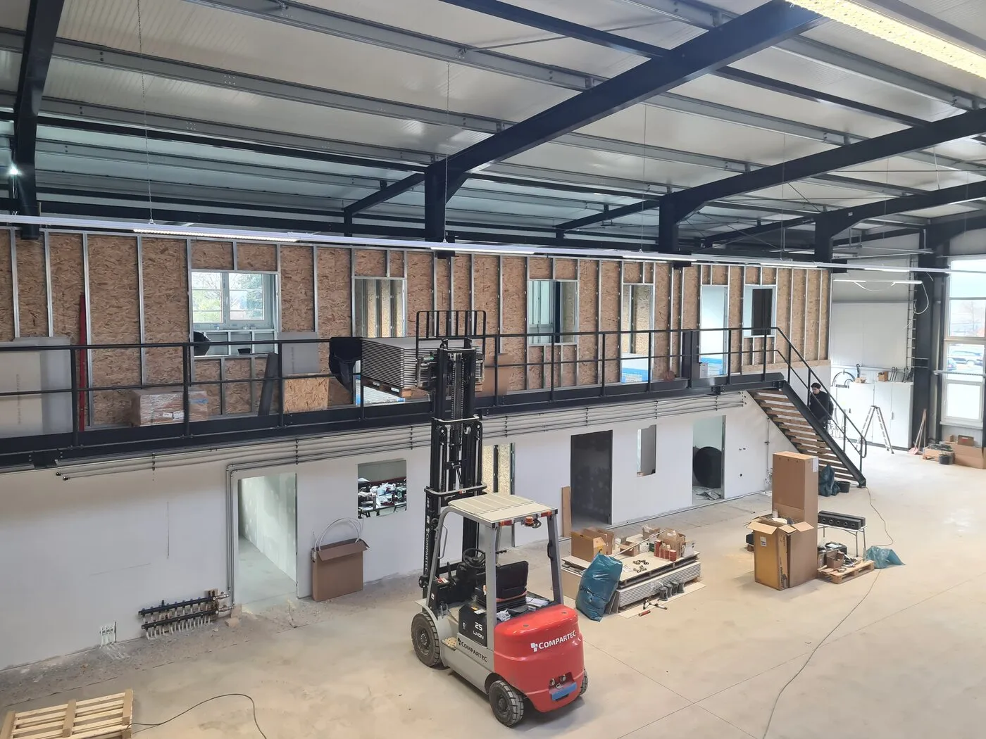 Hall with office wing, mezzanine, stairs and a forklift during fit-out