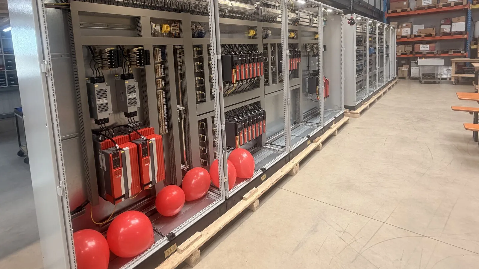 Red balloons in a row of new control cabinets in the hall, for the opening party